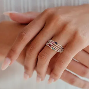 Macro shot of gold-plated stackable rings with baguette-cut colored gemstones and pavé diamonds
