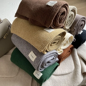 Macro view of assorted ribbed knit scarves in multiple colors with woven brand labels