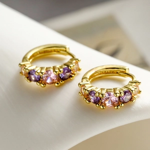 Vista macro di orecchini a cerchio placcati oro con zirconi rosa e viola