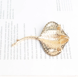 Golden manta ray alloy brooch with enamel finish on a vintage book page background