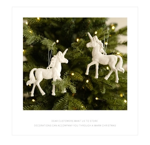 Close-up of white glittery unicorn ornaments hanging on a festive Christmas tree with lights