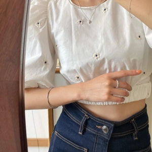 Detail of silver twisted Mobius bracelet styled with white puff sleeve shirt and denim jeans