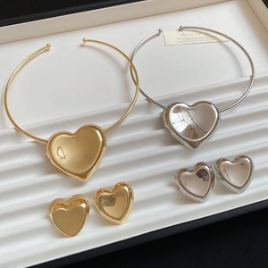 Detailed view of polished heart pendant necklace and stud earrings set in a white box