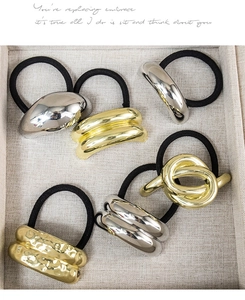 Macro shot of assorted gold and silver geometric metal charms on elastic hair ties