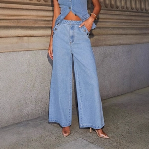 Jean en denim bleu clair à taille haute et jambes larges avec boutons métalliques décoratifs