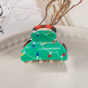 Detail of Christmas green acrylic hair claw with red plaid patterns and rhinestone teeth