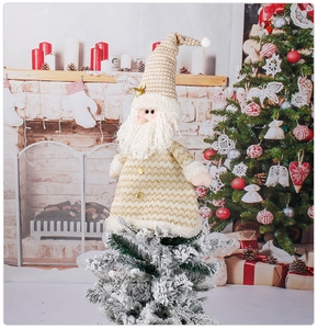 Macro view of Santa Claus knitted doll topper with golden white yarn on snowy Christmas tree