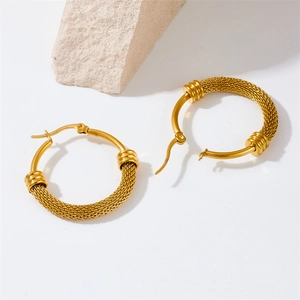 Vintage geometric twisted gold mesh hoop earrings on stone textured background