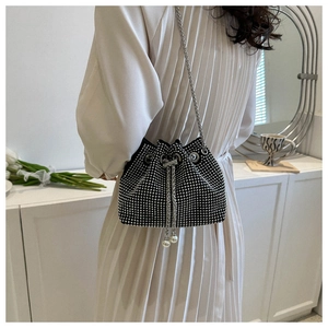 Detail of black rhinestone bucket bag featuring pearl drawstrings and elegant chain strap