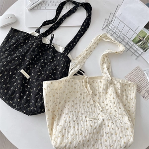 Detailed texture of floral pleated chiffon tote bags in black and beige finishes