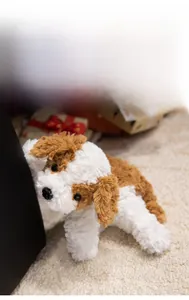 Close-up of soft brown and white plush puppy toy on a cream faux fur rug
