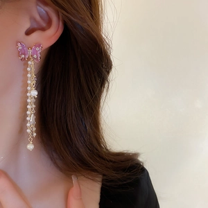 Close-up of elegant butterfly tassel earrings with pink crystals and pearls on model