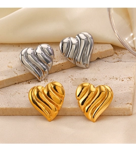 Vue détaillée de clous d'oreilles cœur texturés or et argent sur fond de soie
