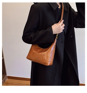 Detail of brown leather crescent bag with embossed fashion text worn by a model