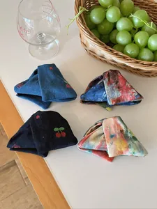 Gros plan de pinces à cheveux en tissu avec motifs tie-dye et floraux sur table blanche