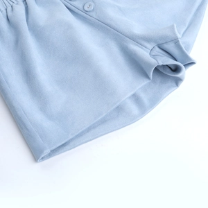 Macro detail of light blue brushed fabric with matching buttons and elastic waistband