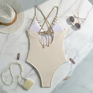 Detail of beige ribbed one-piece swimsuit with lace-up back on marble surface