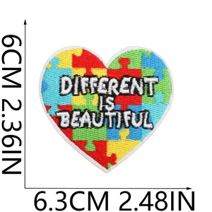 Detail of heart-shaped puzzle embroidery patch with Different is Beautiful slogan