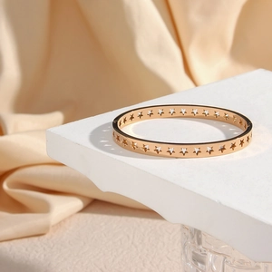 Detail of rose gold bangle with hollow star pattern on a minimalist display stand