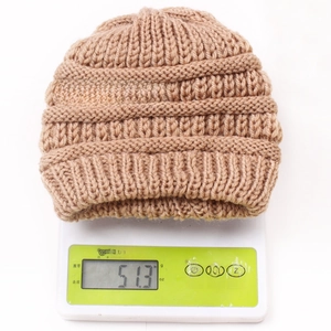 Close-up of a warm beige knit baby hat on a digital scale showing 51.3g weight