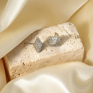 Detail of square silver stud earrings with pavé crystals on beige stone and champagne silk