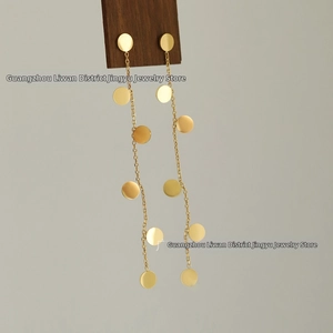 Detailed close-up of long 18K gold plated tassel earrings with polished round sequins