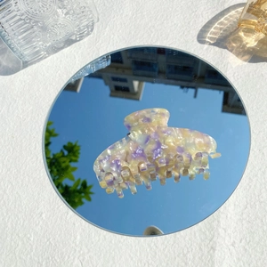 Artistic reflection of a purple marble acetate hair claw clip on a mirror background