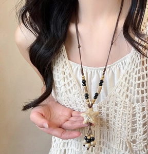 Detail of star ceramic pendant necklace with beads on dark brown leather cord