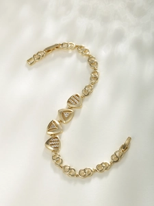 Macro shot of gold geometric triangle charms with pavé cubic zirconia on chain bracelet