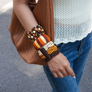 Detail of layered bohemian wood bead bracelets in earthy tones on a model's wrist