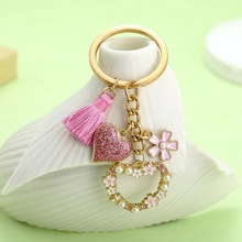 Close-up of pink tassel and glitter heart charms on a gold keychain with pearls
