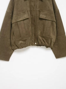 Détail du blouson aviateur en daim vert olive montrant la texture et les grandes poches