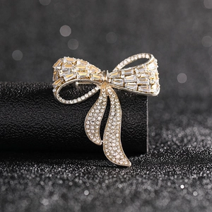 Macro shot of gold bow brooch with rectangular and round crystals on a black base
