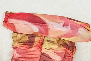 Detail of colorful abstract oil painting print and textured pleated fabric on maxi dress