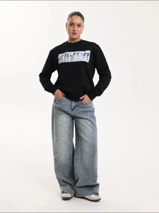 Oversized μαύρο φούτερ με καλλιτεχνικό τύπωμα και φαρδύ τζιν παντελόνι για μοντέρνο στυλ