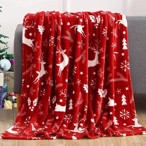 Detail of red Christmas flannel blanket with reindeer and snowflake patterns on a sofa
