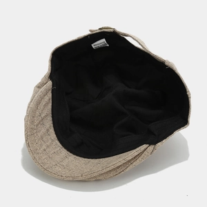 Detail view of newsboy cap interior showing 100% polyester wash label and black lining