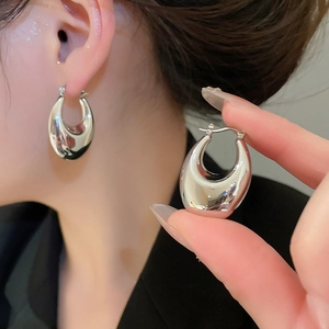 Close-up of polished silver teardrop hoop earrings showing glossy finish and hinge