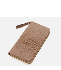Vista detallada de cartera larga marrón con patrón de cocodrillo y correa de muñeca a juego