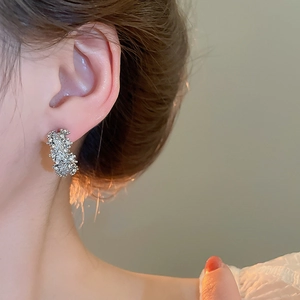 Gros plan de boucles d'oreilles argentées en forme de C avec texture irrégulière