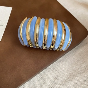 Detail view of gold metal and blue marble resin segments on an elastic bracelet