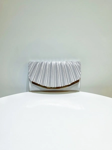 Detail of silver evening clutch bag with radial pleats and gold curved metal trim