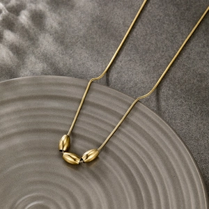 Detail shot of a minimalist 14k gold plated snake chain necklace with three oval beads