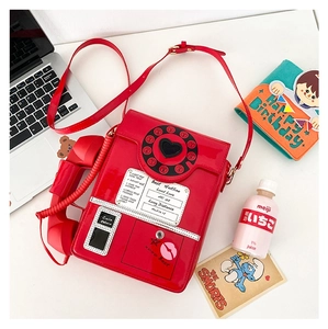 Detail of red retro phone shaped crossbody bag with vintage dial and receiver on table