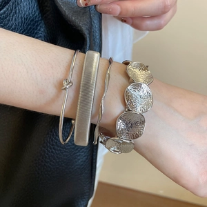Close-up of four-piece silver metal bracelet set with hammered texture and wavy designs