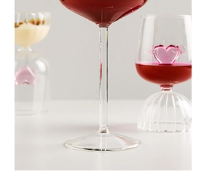 Close-up of glass wine goblet featuring a pink heart shape and delicate glass wings