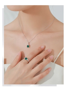 Gros plan d'un ensemble collier et bague en argent S925 avec gemmes vertes émeraude