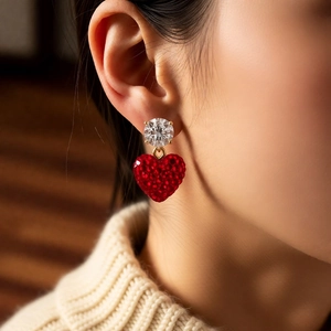Gros plan de boucles d'oreilles cœur rouge avec clous en zircon portées par un mannequin