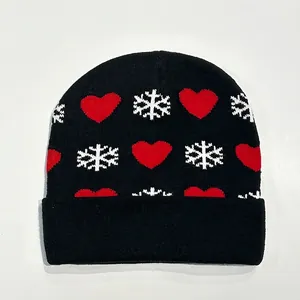 Close-up of black knit beanie featuring red heart and white snowflake festive patterns