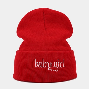 Detailierte Textur der roten Strickmütze mit weißer babygirl-Stickerei auf dem Aufschlag